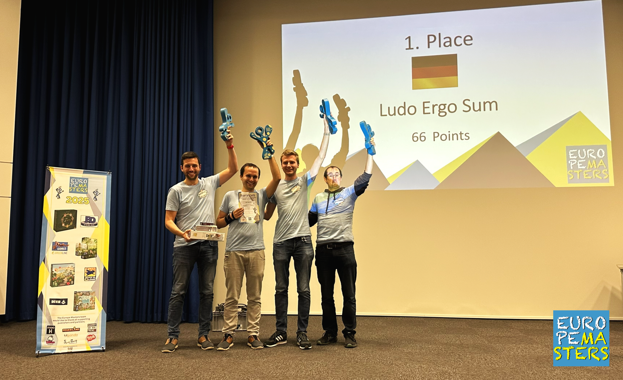 I quattro giocatori tedeschi di Ludo Ergo Sum sul palco degli Europe Masters 2025 con le braccia alzate e i trofei in mano