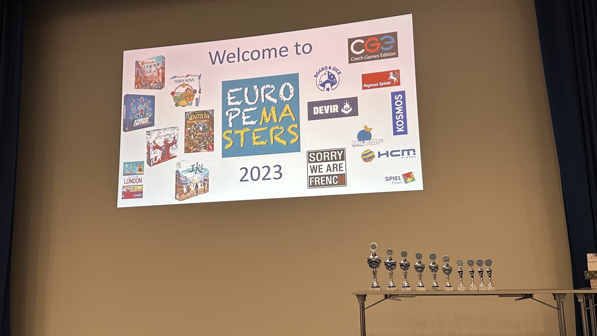 Schermo di benvenuto Europe Masters 2023 con i loghi degli editori sponsor e i trofei pronti